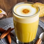 Turmeric Latte, also known as Golden Milk, in a white mug garnished with a sprinkle of turmeric powder and cinnamon sticks.